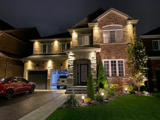night view of house with outside lights showing interlocking brick sidewalk